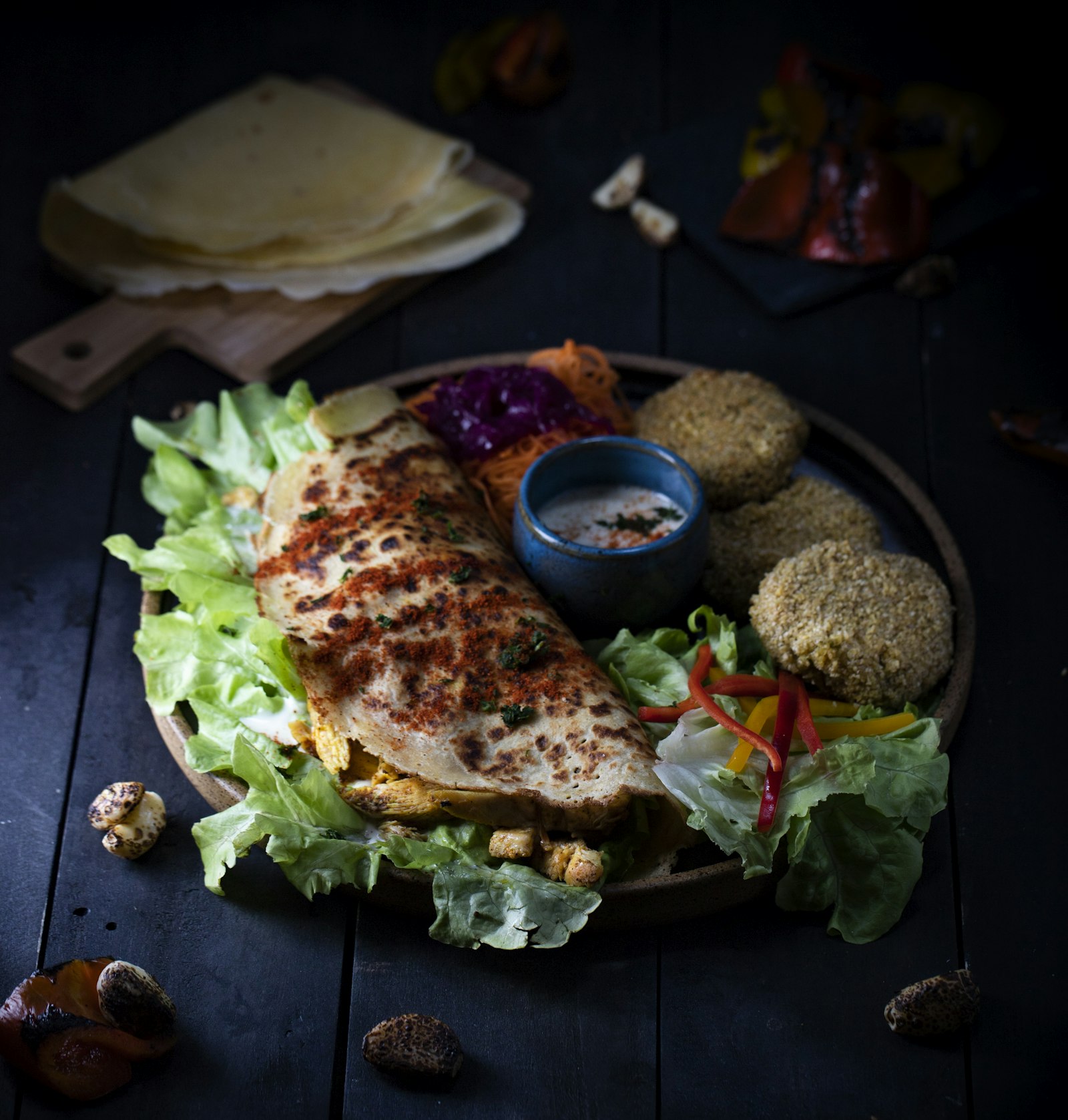 Orientalischer Teller mit gefülltem Fladen, Falafel, frischem Salat und Joghurt-Dip in stimmungsvollem Licht